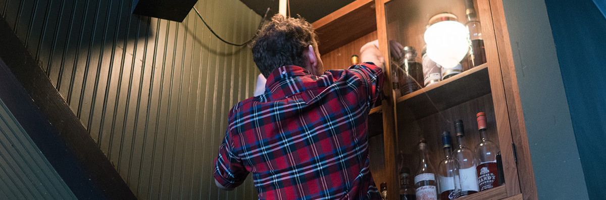 Pulling rare spirits from the cabinet in the back of the bar