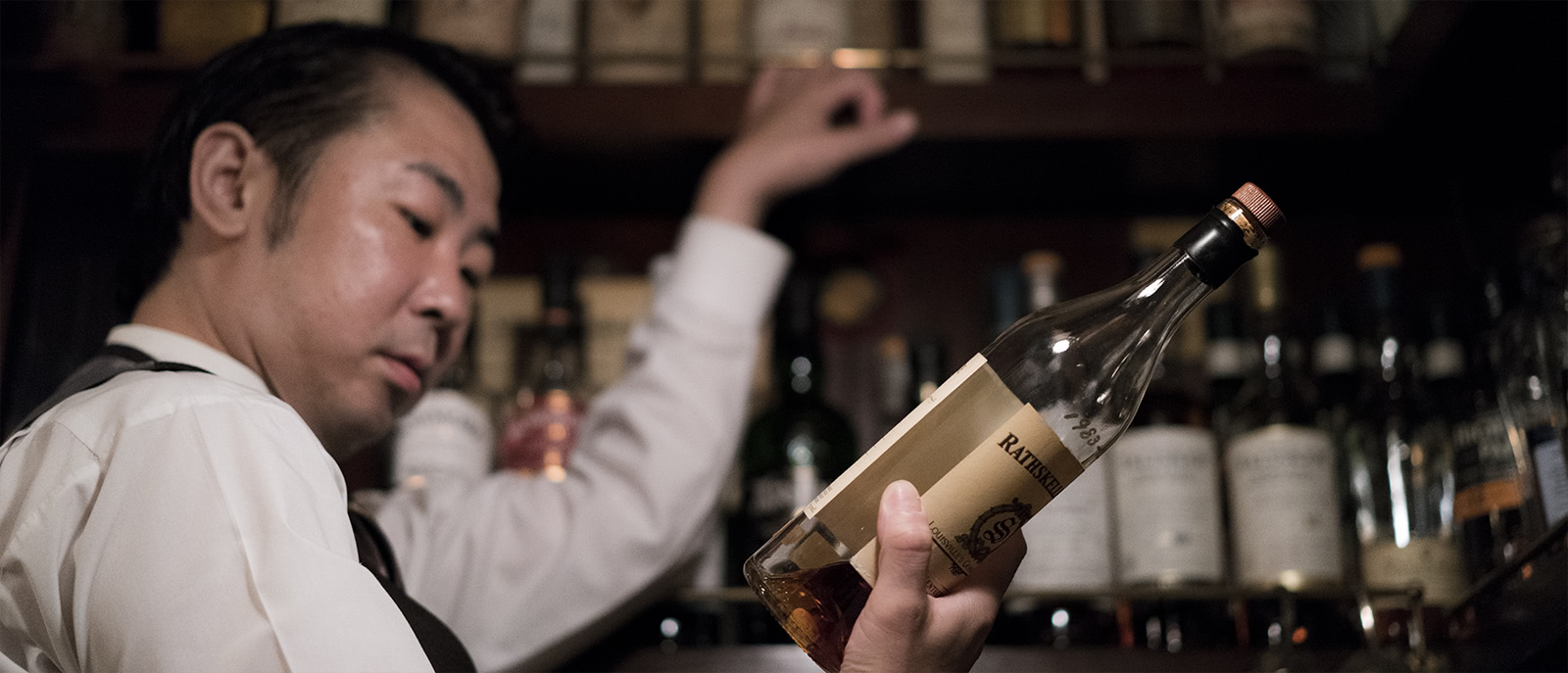 The bartender inspects a bottle of Rathskeller Rye